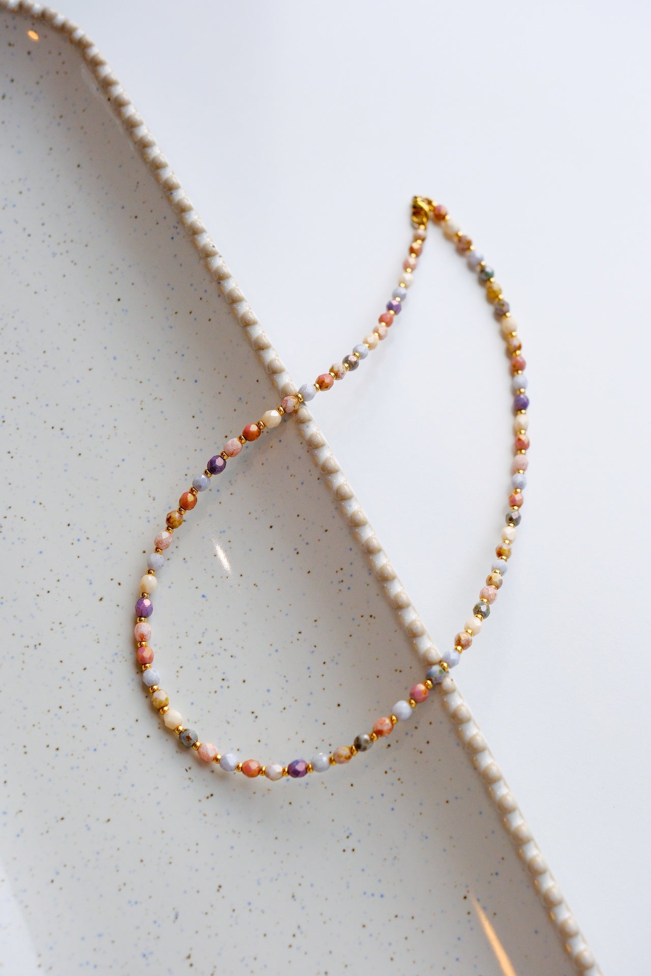 Multicolored beaded necklace on a textured white surface